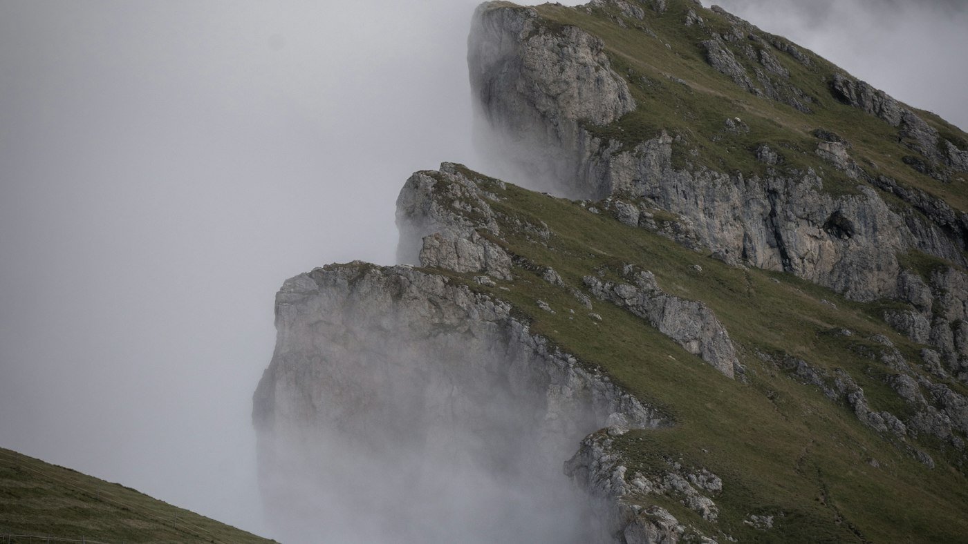 Persona ascendiendo una cresta de montaña entre niebla