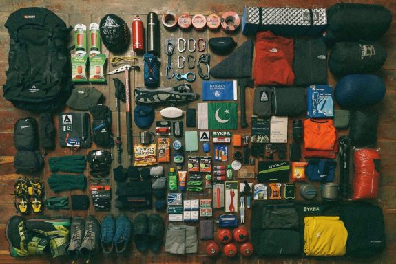 Variedad de equipo de camping y senderismo dispuestos ordenadamente sobre una superficie plana.