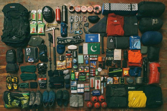 Variedad de equipo de camping y senderismo dispuestos ordenadamente sobre una superficie plana.